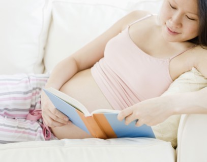 Pregnant Asian woman reading book