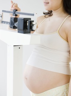 Pregnant Asian woman weighing herself