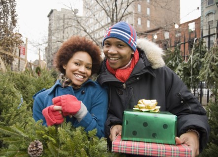 African couple in Christmas tree lot holding presents