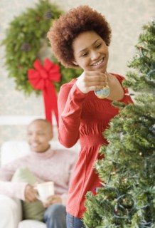 Mixed race woman placing ornament on Christmas tree