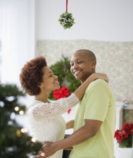 African couple kissing underneath mistletoe