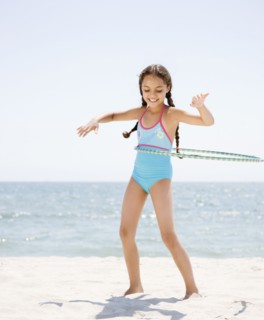 Hispanic girl playing with plastic hoop on beach