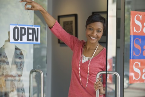 African business owner hanging open sign on shop door