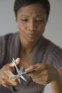Frustrated African woman cutting up credit card