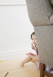 Toddler girl hiding behind chair