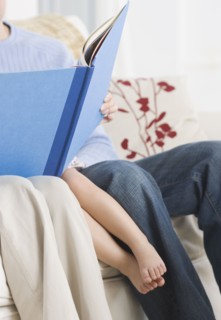Parents reading to daughter on sofa