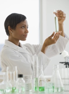 African scientist looking at vial of liquid