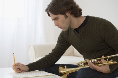 Hispanic man composing trumpet music