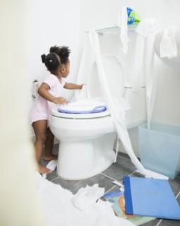 African American girl spreading toilet paper around bathroom
