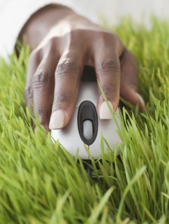 African woman using computer mouse in grass