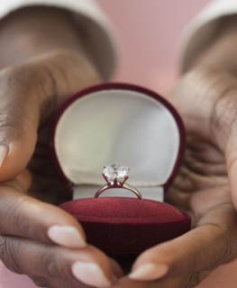 African woman holding engagement ring in box