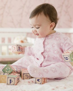 Mixed race baby girl playing with alphabet blocks