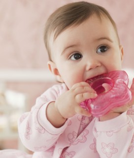 Mixed race baby girl chewing on plastic toy