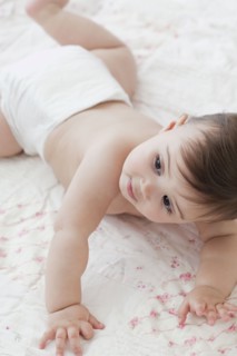 Mixed race baby girl crawling on blanket