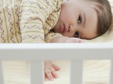 Mixed race baby girl laying in crib