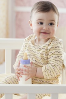 Mixed race baby girl holding bottle