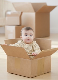Mixed race baby girl sitting in cardboard box