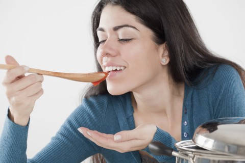 Hispanic woman tasting tomato sauce