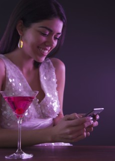 Hispanic woman text messaging in nightclub