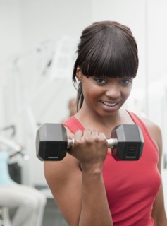 African woman using hand weight in health club