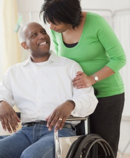 African woman pushing husband in wheelchair