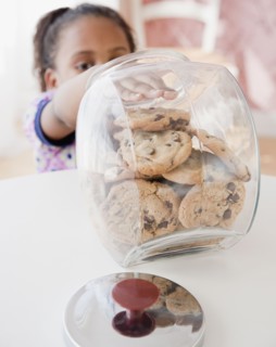 African girl taking cookie from jar