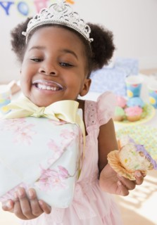 African girl eating cupcake and carrying gift