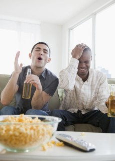 Men drinking beer and watching sports on television