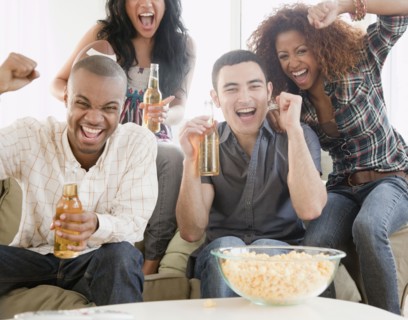 Friends drinking beer and watching football on television
