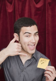 Mixed race man holding Call Me sticky note and gesturing