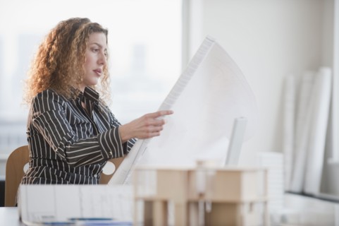 Hispanic woman looking at blueprints