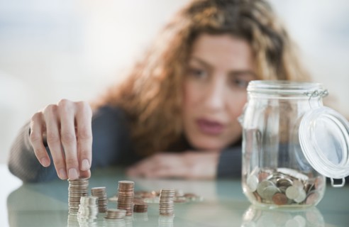 Hispanic woman counting coins from jar