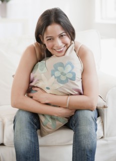 Hispanic woman hugging pillow on sofa