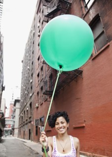 Mixed race woman holding balloon on urban street