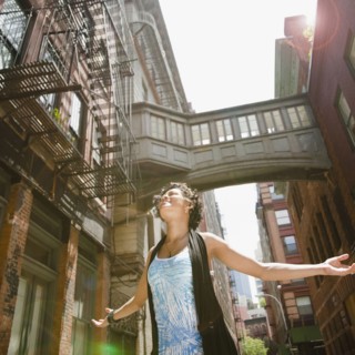Mixed race woman with arms outstretched on urban street