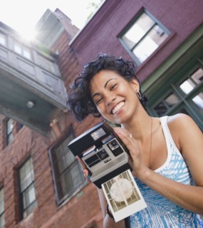 Mixed race woman holding instant camera