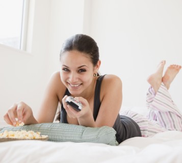 Mixed race woman eating popcorn and watching television