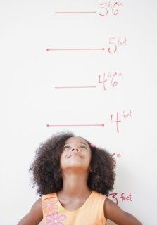 Mixed race girl standing near height chart