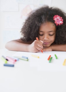 Mixed race girl drawing with crayons