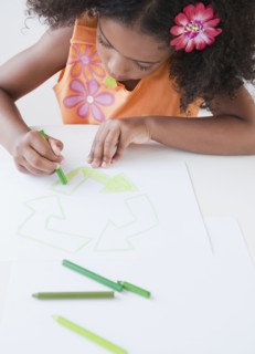 Mixed race girl drawing recycling symbol with crayons