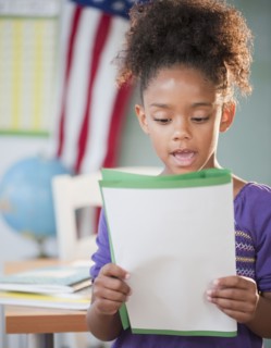 Mixed race girl reading report at school