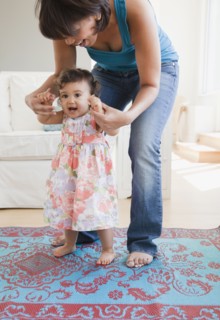 Hispanic mother helping daughter learn to walk