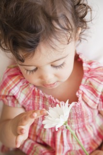 Hispanic baby girl looking at flower