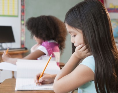 Mixed race school girl writing in notebook
