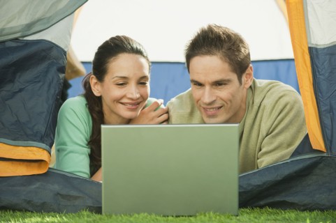 Hispanic couple using laptop in tent