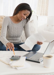 Mixed race woman paying bills in living room