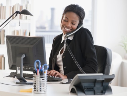 Mixed race businesswoman typing and talking on phone