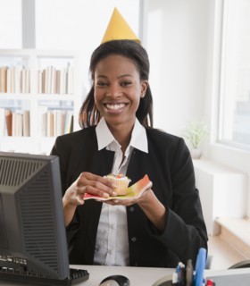 Mixed race businesswoman eating birthday cupcake