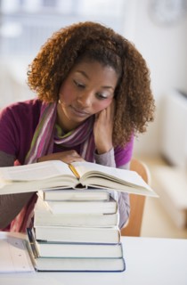 Mixed race woman looking at stack of books