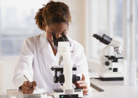 Mixed race scientist peering into microscope